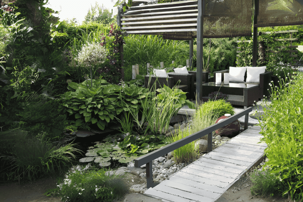 Naturnaher Garten mit Teichanlage, Seerosen und einer modernen Holzbrücke, eingebettet in üppige Stauden und Gräser als Beispiel für Natural Crafted Landscapes.