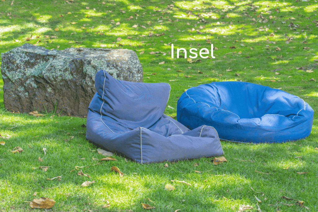 Zwei Sitzsäcke auf einer freien Rasenfläche, die ohne Sichtschutz im Raum platziert sind.