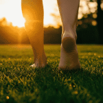 zwei nackte Beine die auf taufrischem grünen Rasen laufen