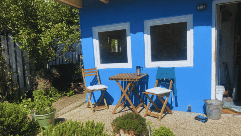 Blau gestrichene Gartenlaube mit Sitzplatz im Schrebergarten