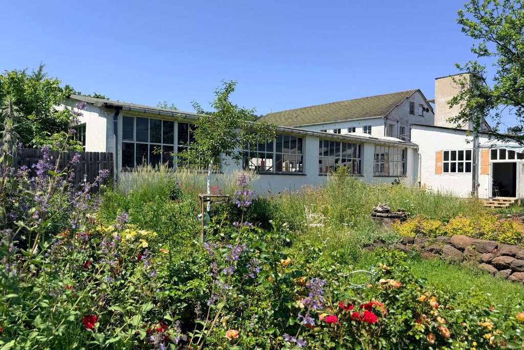 Garten der Nouvabrik mit blühenden Staudenbeeten vor der alten Fabrikhalle